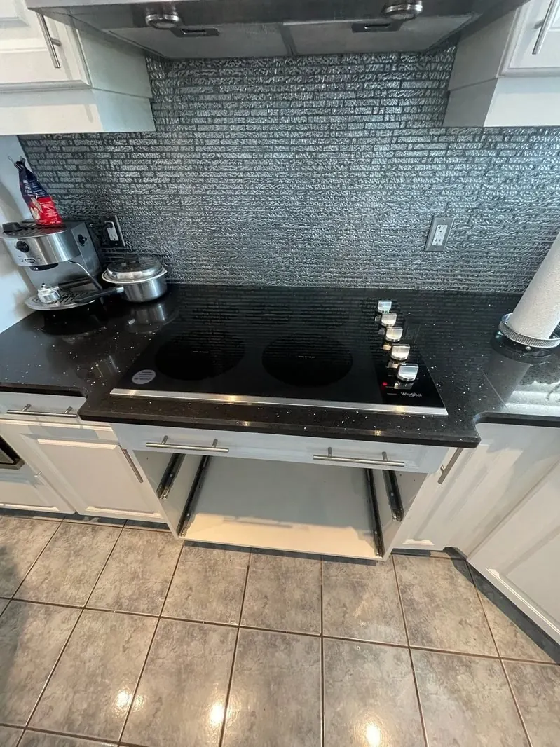 Black glass cooktop installed in a dark granite counter under a range hood